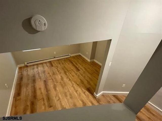 laundry area featuring light wood-type flooring and a baseboard radiator