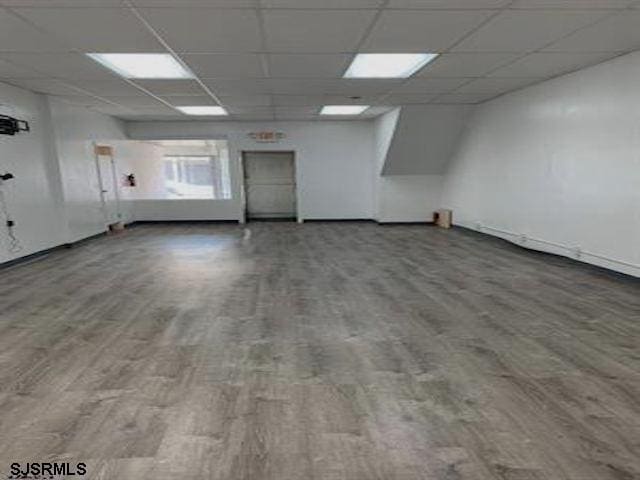 unfurnished room with a drop ceiling and wood-type flooring