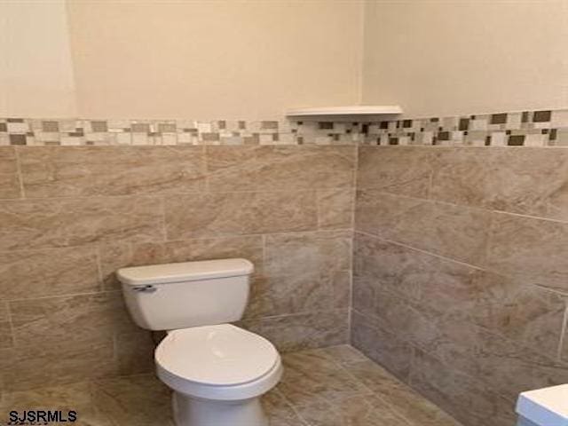 bathroom featuring tile walls and toilet