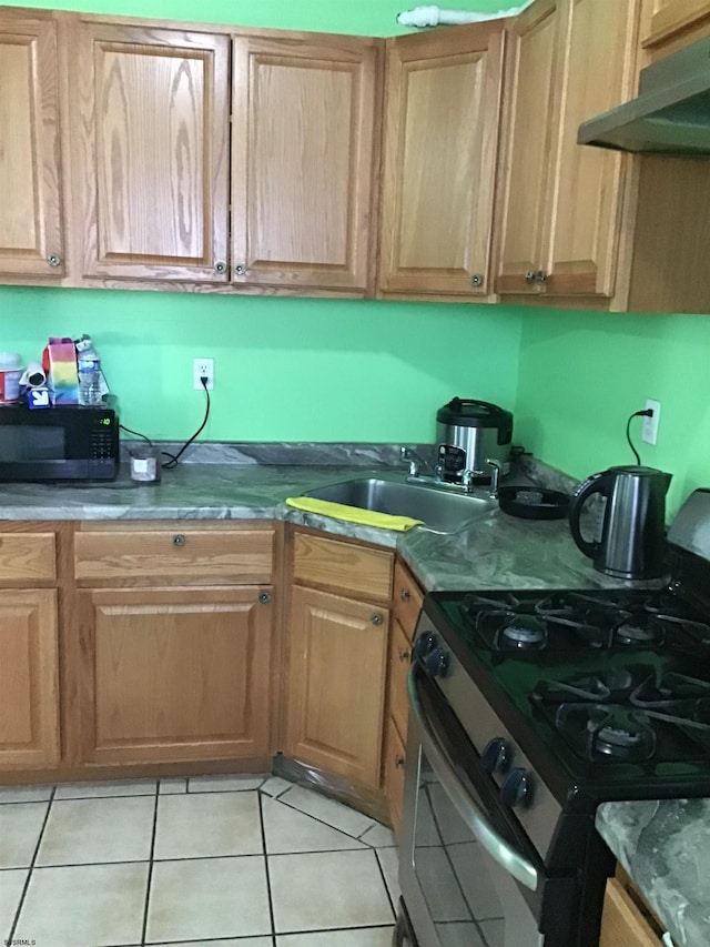 kitchen with gas range oven, wall chimney exhaust hood, sink, and light tile floors