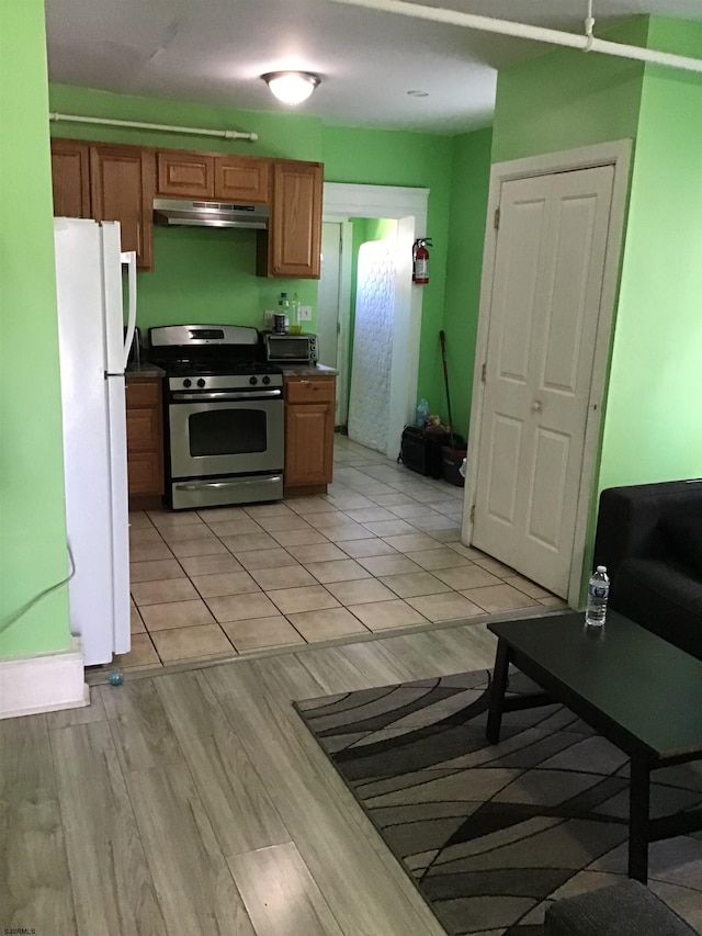 kitchen with stainless steel range, white fridge, and light wood-type flooring