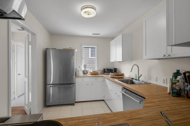 kitchen with light tile flooring, sink, stainless steel appliances, and white cabinetry