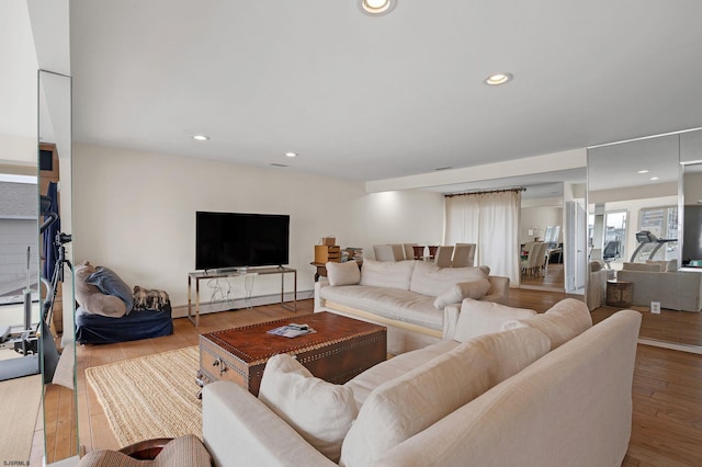 living room with a baseboard heating unit and light wood-type flooring