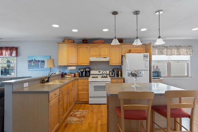 kitchen with hanging light fixtures, white appliances, light hardwood / wood-style floors, sink, and a breakfast bar area