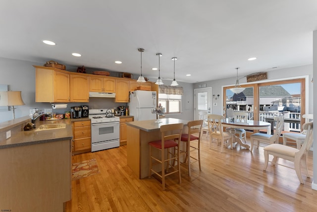 kitchen featuring pendant lighting, a kitchen island, white appliances, light hardwood / wood-style floors, and sink