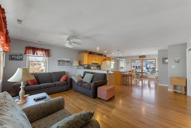 living room with ceiling fan, light hardwood / wood-style flooring, and a healthy amount of sunlight