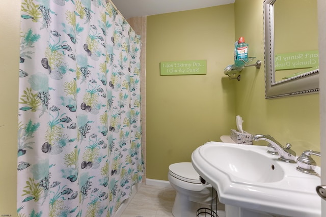 bathroom with toilet, tile flooring, and sink