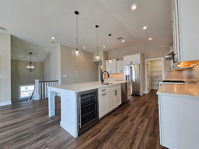 kitchen featuring decorative backsplash, a kitchen island with sink, beverage cooler, and stainless steel appliances