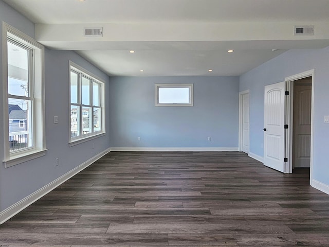 spare room featuring a wealth of natural light and dark wood-type flooring