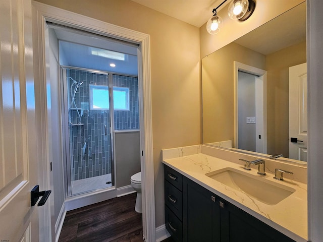 bathroom with wood-type flooring, vanity, toilet, and a shower with door