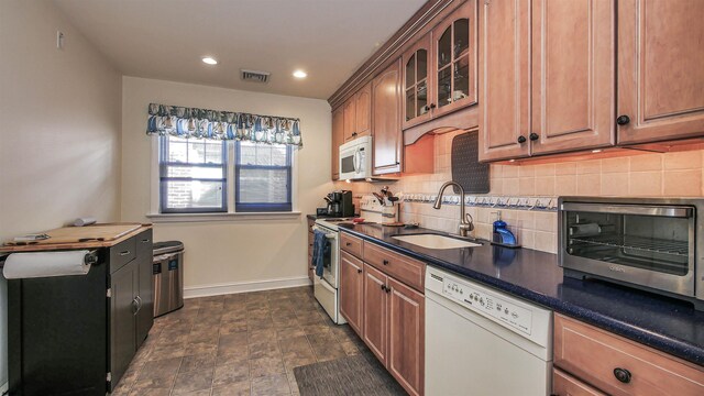 kitchen with sink, white appliances, backsplash, and dark tile flooring