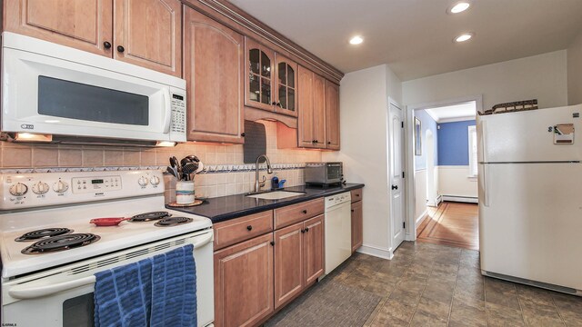 kitchen with tasteful backsplash, a baseboard radiator, dark tile flooring, sink, and white appliances