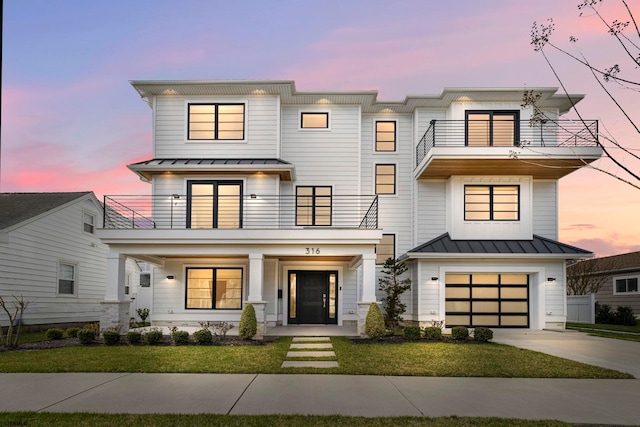 view of front of home with a garage, a balcony, and a lawn