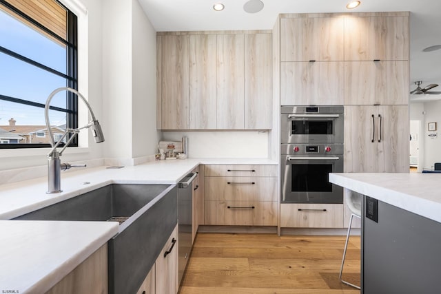 kitchen featuring light hardwood / wood-style flooring, ceiling fan, stainless steel appliances, and light brown cabinets