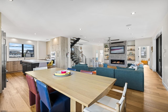 dining area with light hardwood / wood-style flooring, ceiling fan, and a fireplace