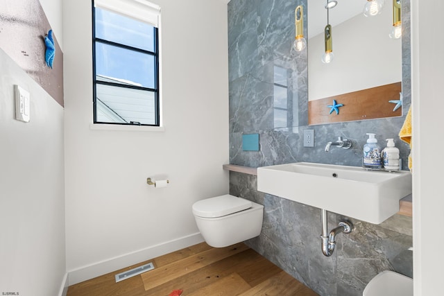 bathroom with tile walls, sink, toilet, and hardwood / wood-style flooring