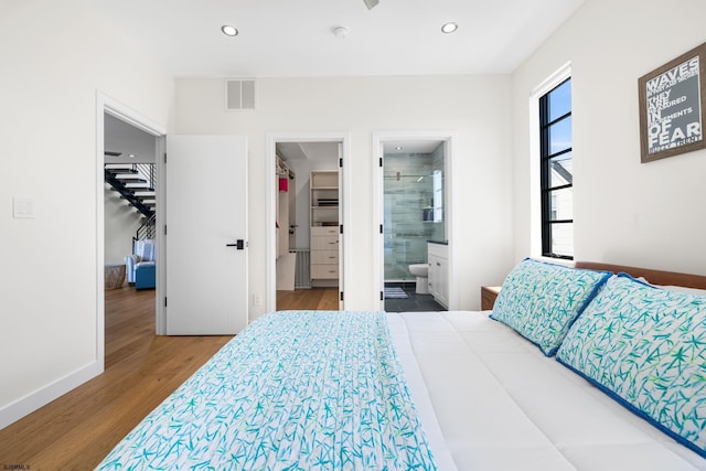 bedroom with wood-type flooring, a spacious closet, ensuite bathroom, and a closet