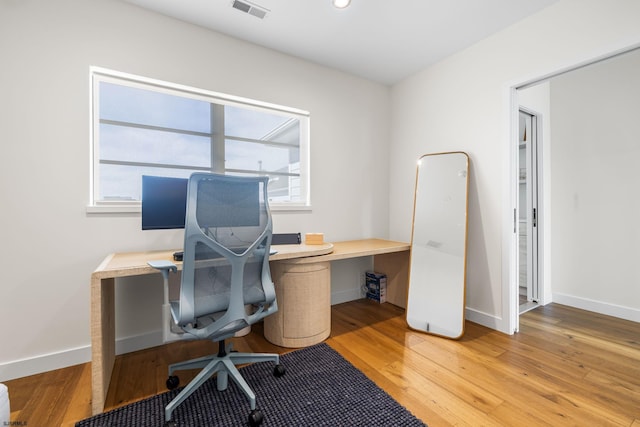 home office with built in desk and light hardwood / wood-style floors