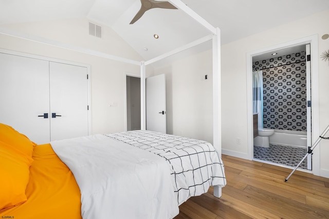 bedroom with a closet, ensuite bath, vaulted ceiling, hardwood / wood-style flooring, and ceiling fan