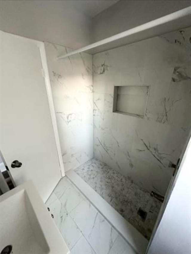 bathroom with a tile shower and tile floors