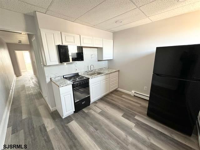 kitchen featuring a drop ceiling, black appliances, and light wood-type flooring