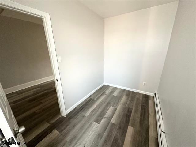 empty room featuring a baseboard radiator and dark wood-type flooring