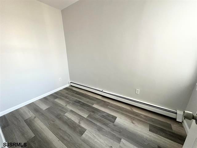 spare room with dark hardwood / wood-style floors and a baseboard radiator