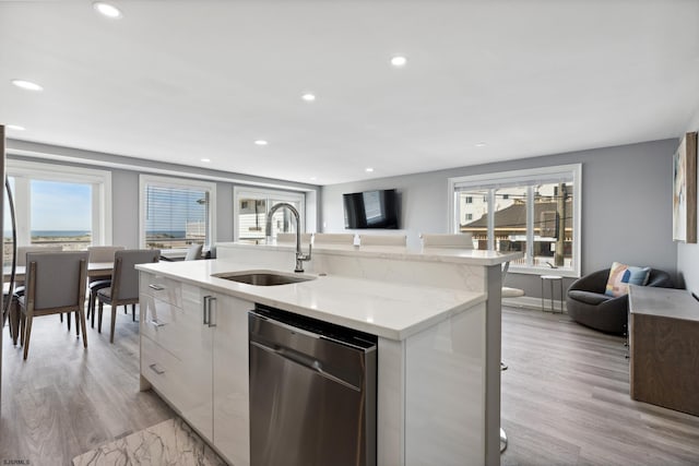 kitchen featuring stainless steel dishwasher, sink, a healthy amount of sunlight, and light hardwood / wood-style floors