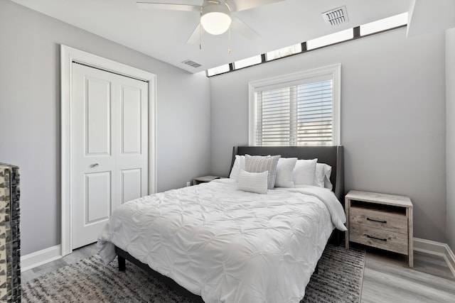 bedroom featuring light hardwood / wood-style flooring, ceiling fan, and a closet