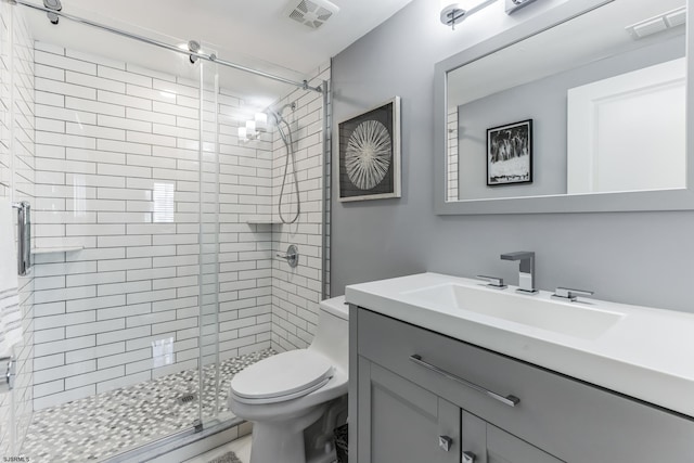 bathroom featuring toilet, vanity, and a shower with shower door