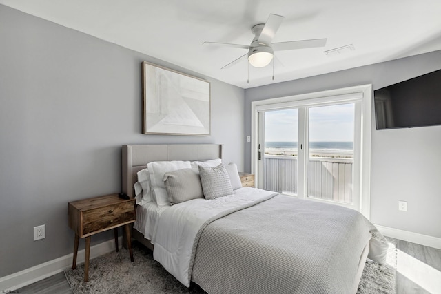 bedroom featuring ceiling fan, a water view, and dark hardwood / wood-style floors