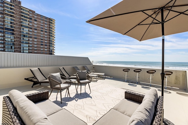 view of patio featuring a view of the beach, outdoor lounge area, a balcony, and a water view