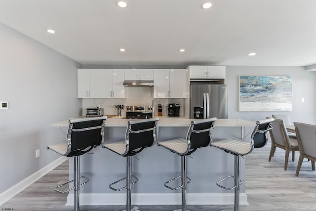 kitchen with a breakfast bar area, white cabinets, and stainless steel fridge with ice dispenser