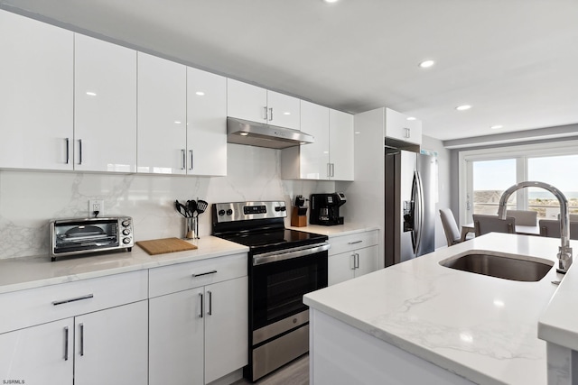 kitchen with light stone counters, stainless steel appliances, backsplash, sink, and white cabinetry