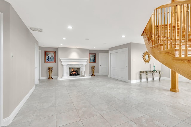 unfurnished living room featuring light tile floors and a high end fireplace