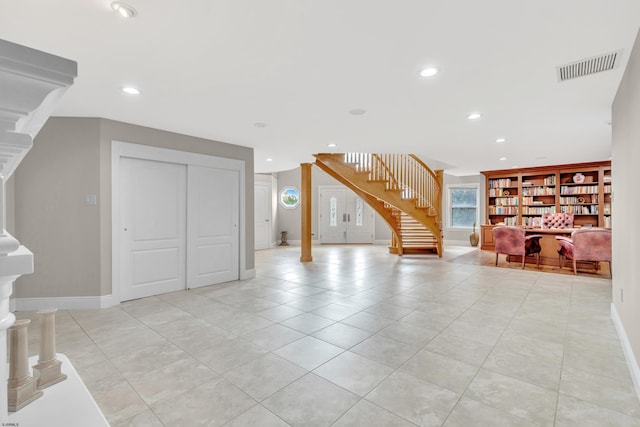 unfurnished living room featuring decorative columns and light tile flooring