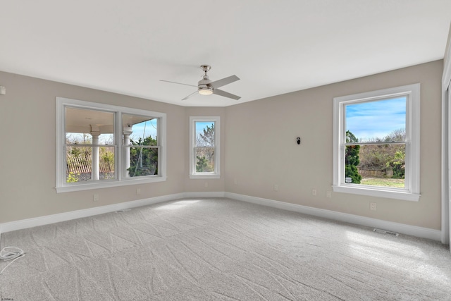 carpeted empty room with a wealth of natural light and ceiling fan