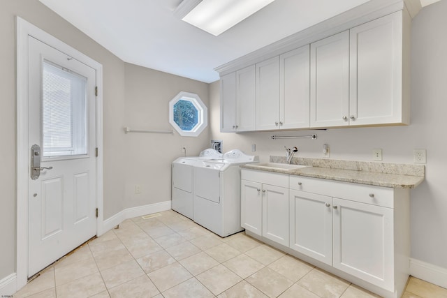 clothes washing area featuring cabinets, sink, light tile floors, and washing machine and clothes dryer