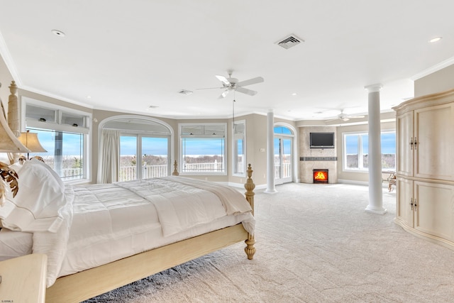 carpeted bedroom with ornamental molding, access to outside, ceiling fan, and a large fireplace