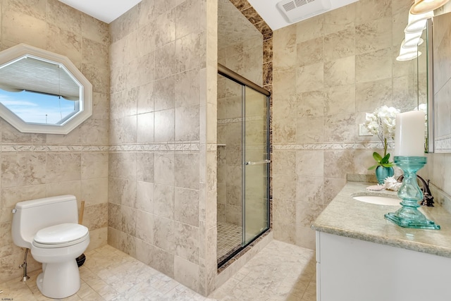 bathroom with vanity, toilet, tile walls, and a shower with door