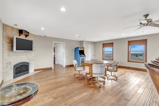 dining room featuring light hardwood / wood-style flooring, tile walls, ceiling fan, and a fireplace