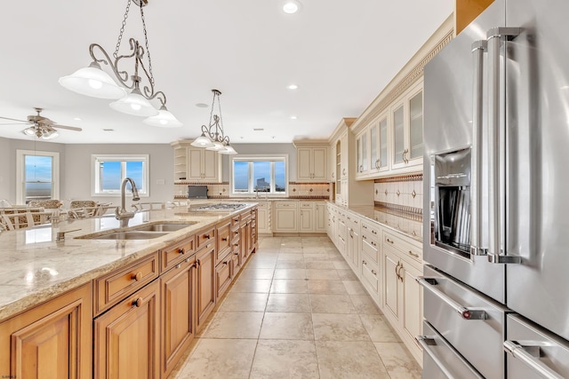 kitchen featuring light stone counters, light tile floors, sink, decorative light fixtures, and stainless steel appliances