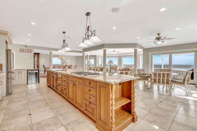 kitchen featuring wine cooler, a kitchen island with sink, decorative light fixtures, light stone countertops, and appliances with stainless steel finishes