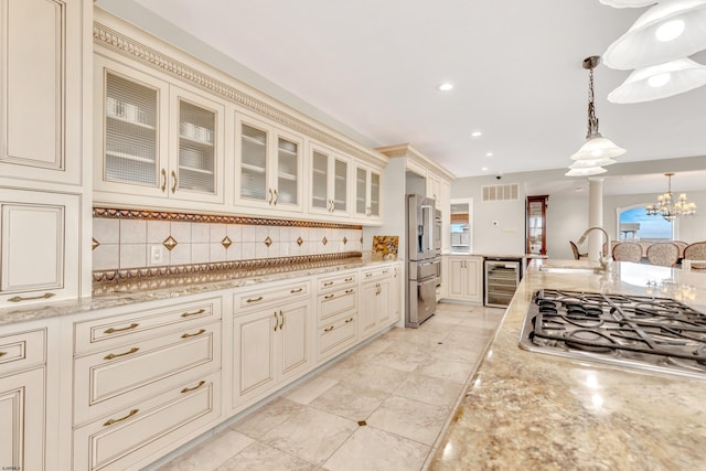 kitchen featuring decorative light fixtures, tasteful backsplash, beverage cooler, appliances with stainless steel finishes, and cream cabinetry