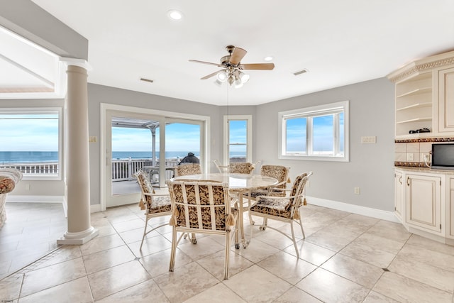 tiled dining area featuring decorative columns, ceiling fan, and a water view