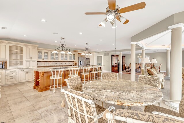 tiled dining room featuring ornate columns and ceiling fan