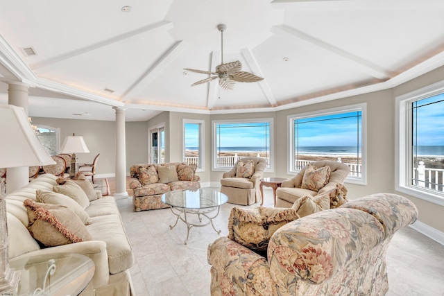 living room featuring a wealth of natural light, ornate columns, ceiling fan, and a water view