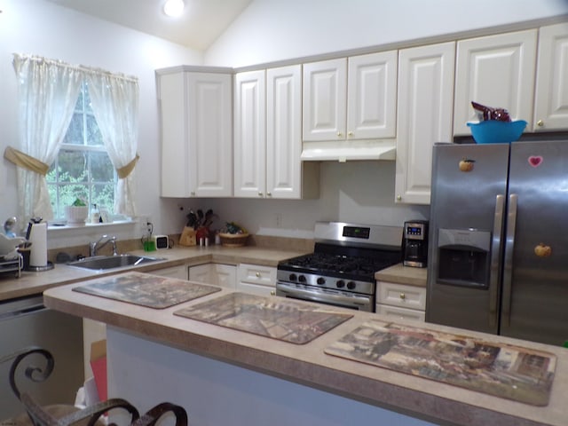 kitchen featuring appliances with stainless steel finishes, sink, vaulted ceiling, and white cabinetry