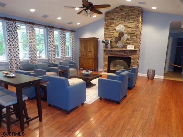 living room with lofted ceiling, wood-type flooring, and a stone fireplace