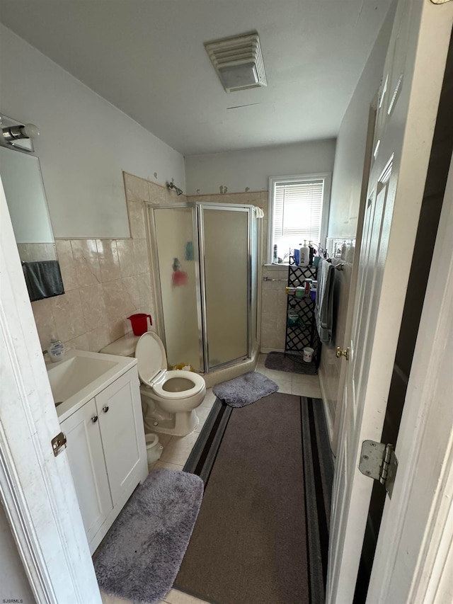 bathroom featuring tile flooring, tile walls, vanity with extensive cabinet space, walk in shower, and toilet